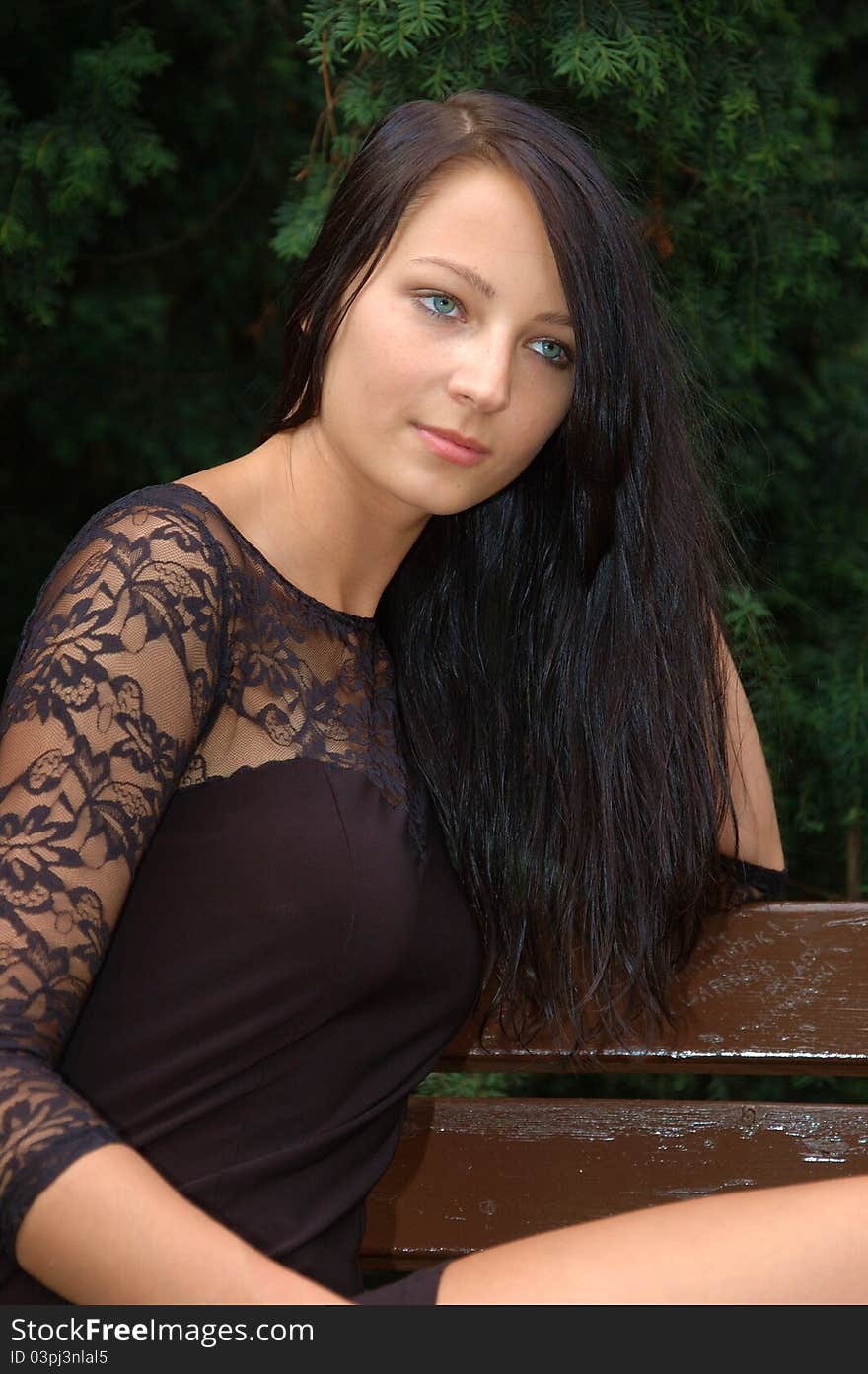 Pretty female model, wearing black skirt. Polish girl sitting at the bank in park. Pretty female model, wearing black skirt. Polish girl sitting at the bank in park.