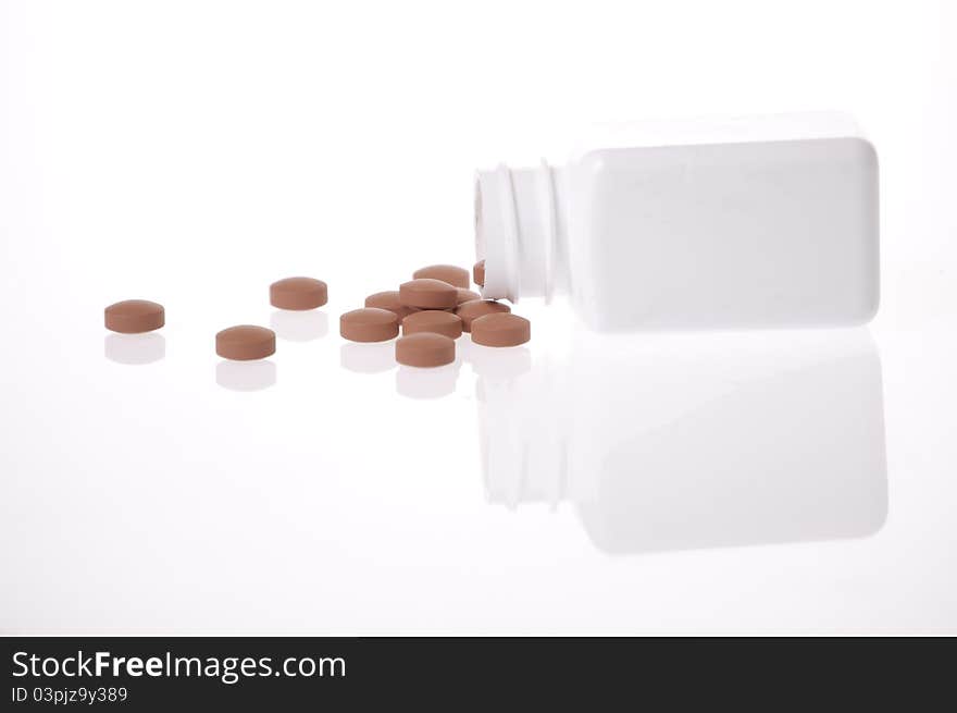 A white pill bottle with red generic pills on a white background. A white pill bottle with red generic pills on a white background.