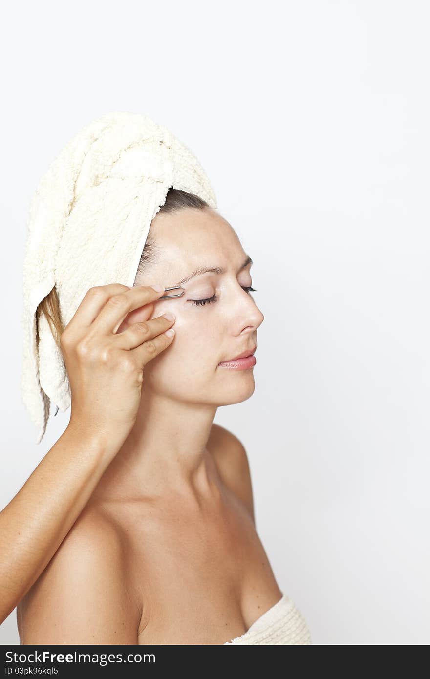 Woman’s eyebrows are plucked by a beautician