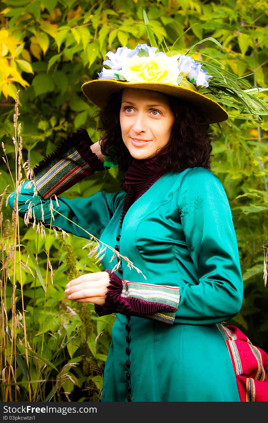 A beautiful woman in a green vintage dress and yellow hat