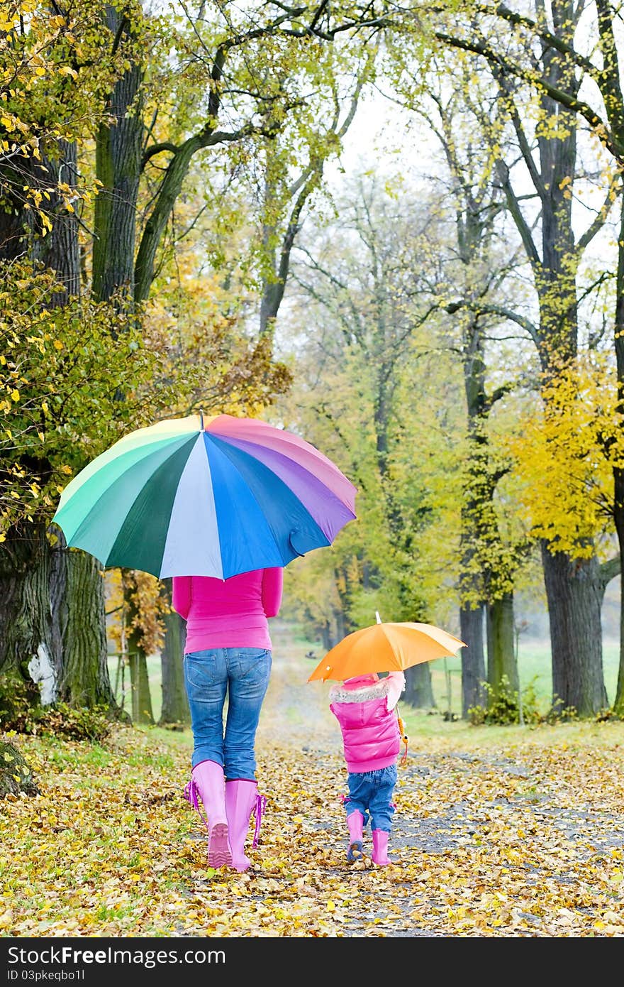 Mother and her daughter with umbrellas in autumnal alley. Mother and her daughter with umbrellas in autumnal alley