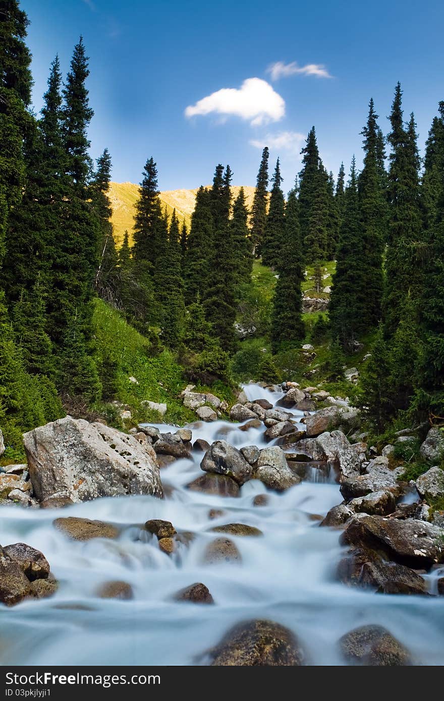 Long exposure image of mountain river falling and flowing trough stone at nature