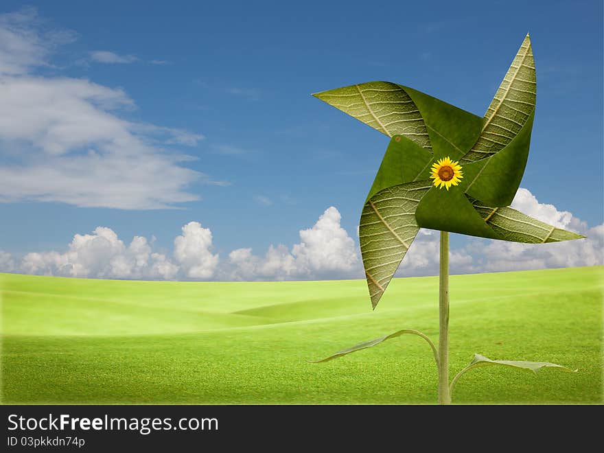 Green leaves windmill on meadow with blue sky