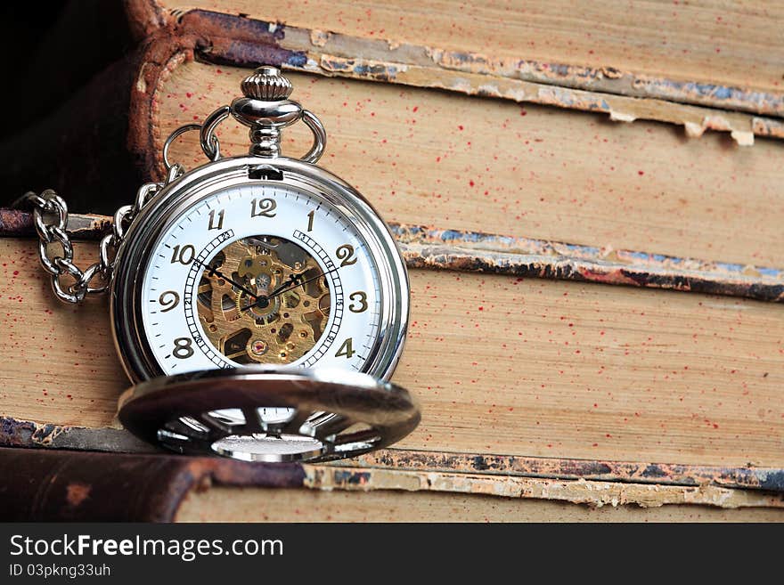 Vintage pocket watch with open lid on background with old books. Vintage pocket watch with open lid on background with old books