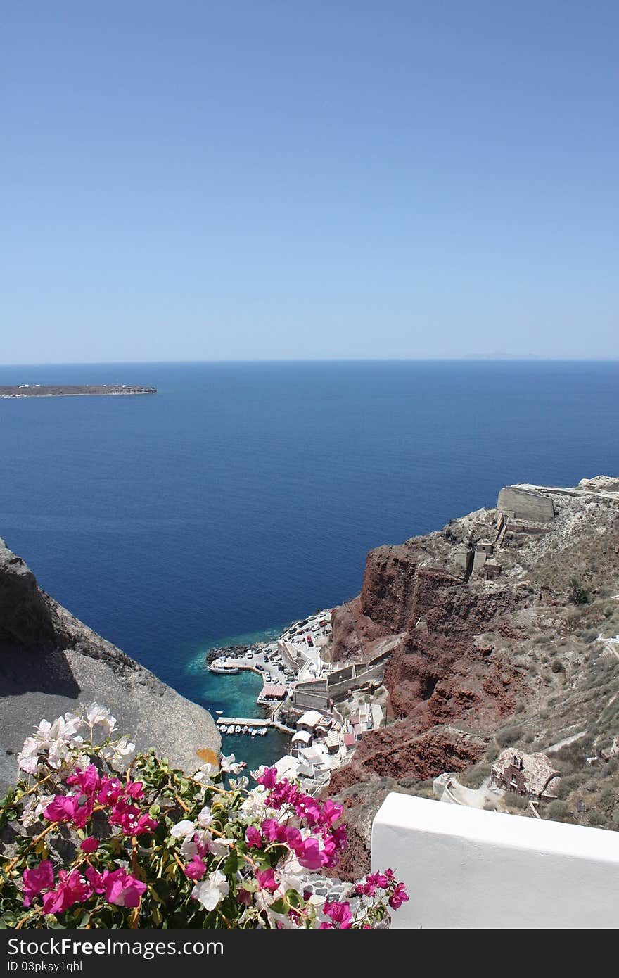 The Greek mountains against the turquoise sea and pink flowers, Santorini. The Greek mountains against the turquoise sea and pink flowers, Santorini