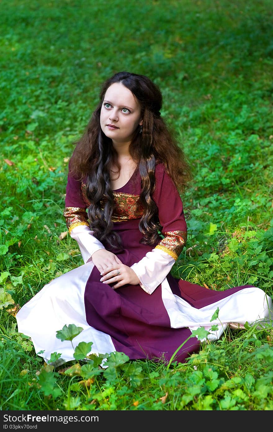 Beautiful woman in vintage dress sitting on the grass