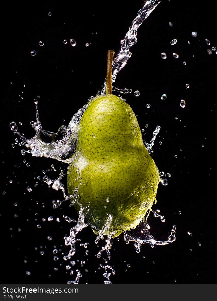 Pear suspended in air splashed with water, isolated on a black background. Pear suspended in air splashed with water, isolated on a black background.