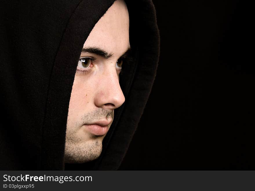 Handsome young man with hood against black background