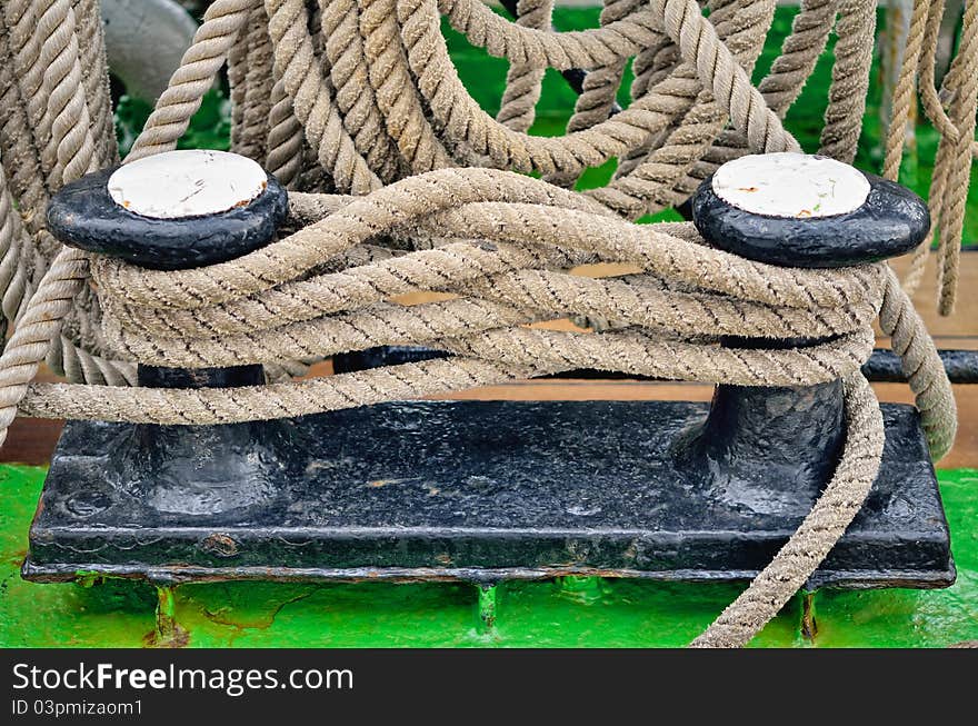 Heavy twisted ropes on the cast iron mooring bollard