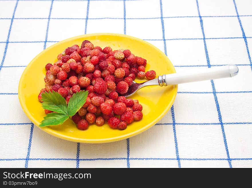 Red strawberries on a plate with spoon