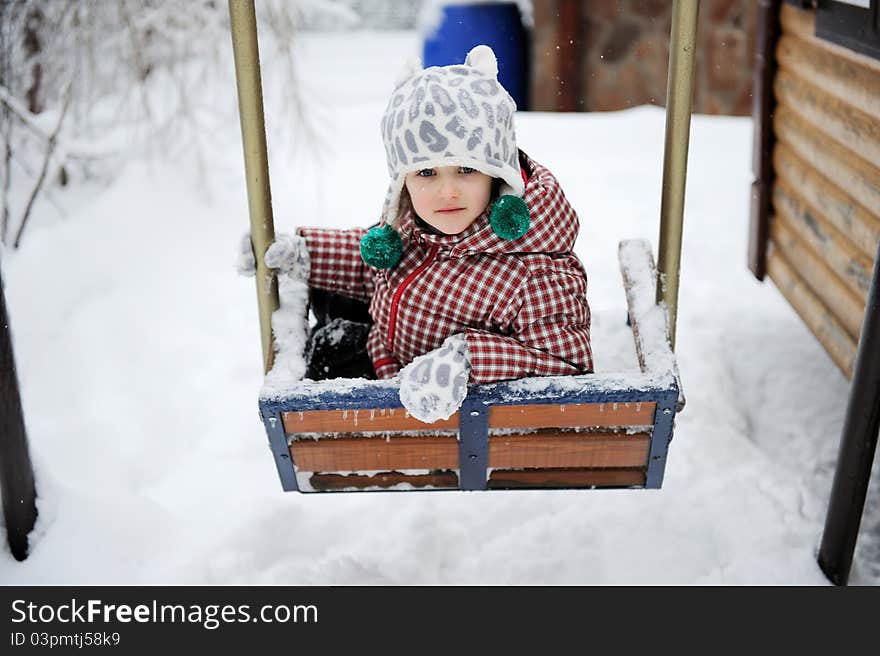 Adorable child girl in red winter coat has fun on seesaw. Adorable child girl in red winter coat has fun on seesaw