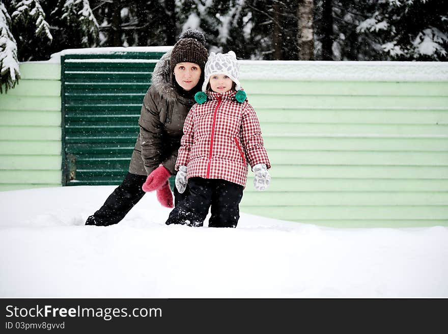 Portrait of young mother and her adorable daughter in the snow on a bright winter day. Portrait of young mother and her adorable daughter in the snow on a bright winter day