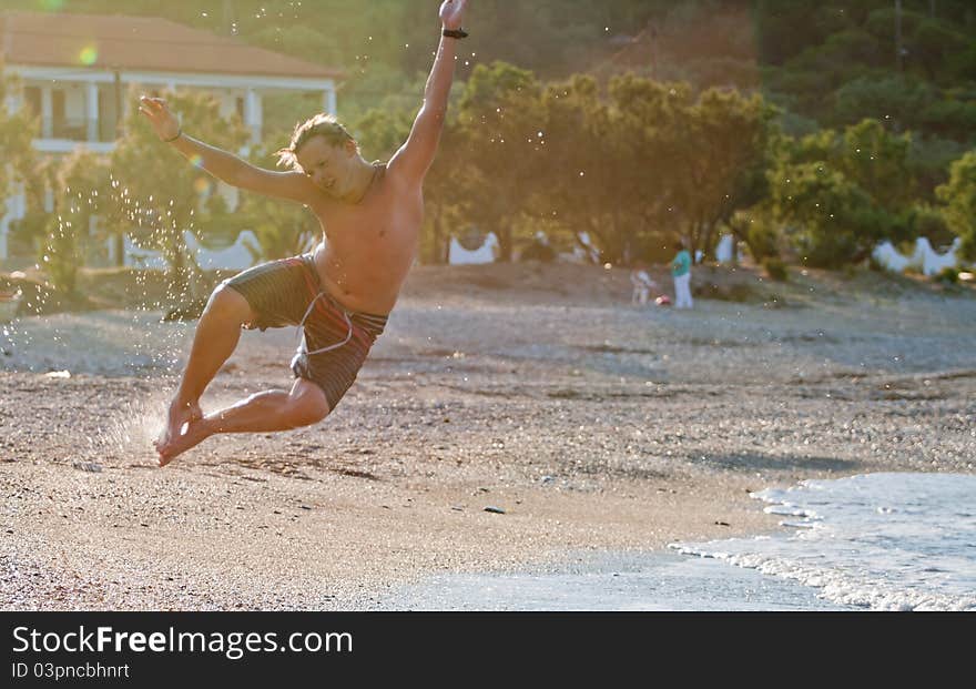 Teenager do an acrobatic figure in the air on the beach. Teenager do an acrobatic figure in the air on the beach