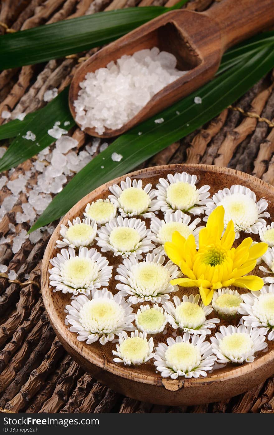 Spa set with sea salt and flowers on the wooden background