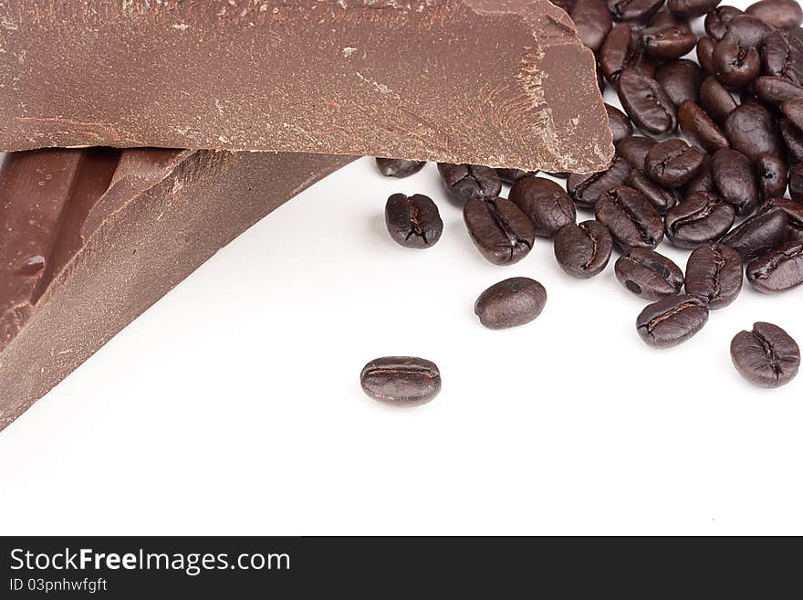 Bitter chocolate in pieces with coffee grains on a white background.