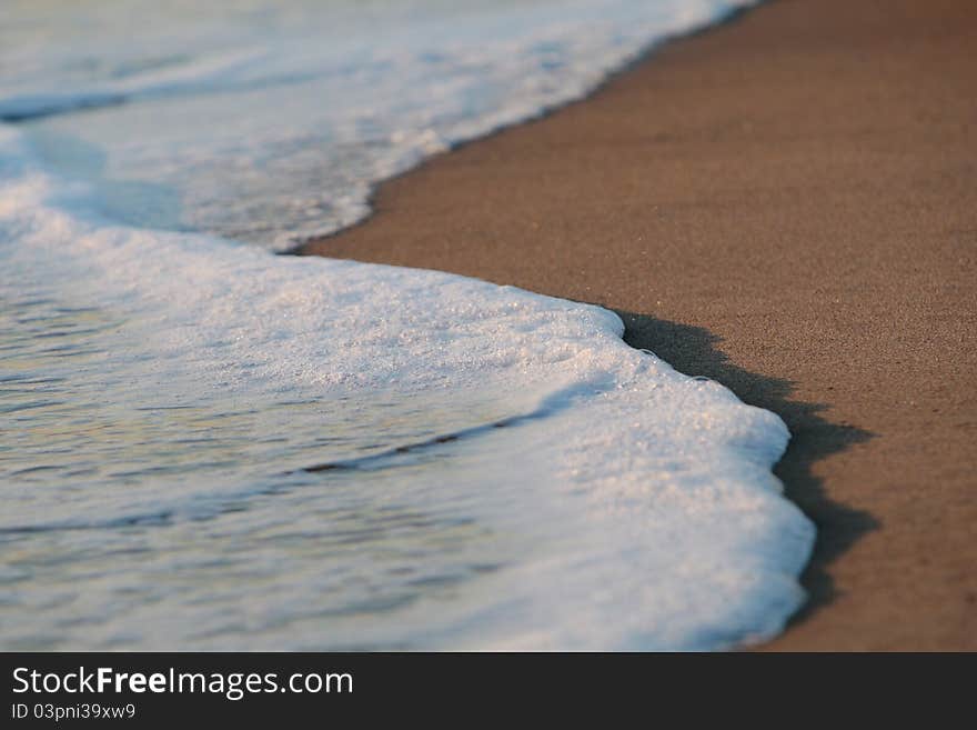 A wave thinning out of the sand of a beach. A wave thinning out of the sand of a beach