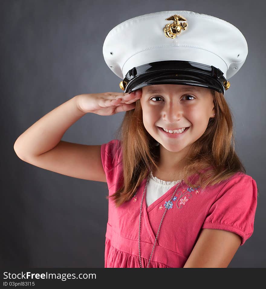 A patriotic girl salutes while wearing a military hat. A patriotic girl salutes while wearing a military hat