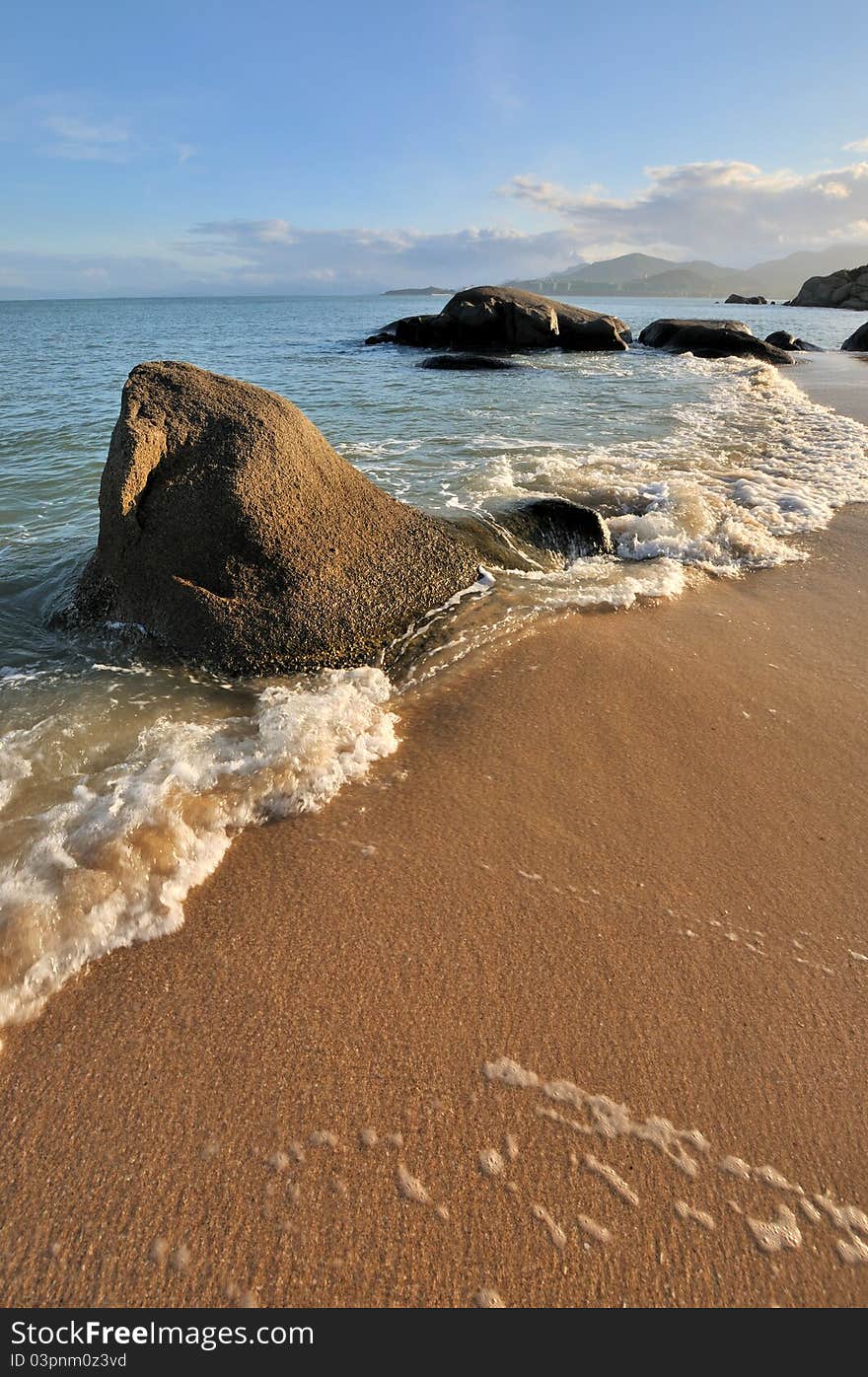 Sea coast rock and wave in sunset