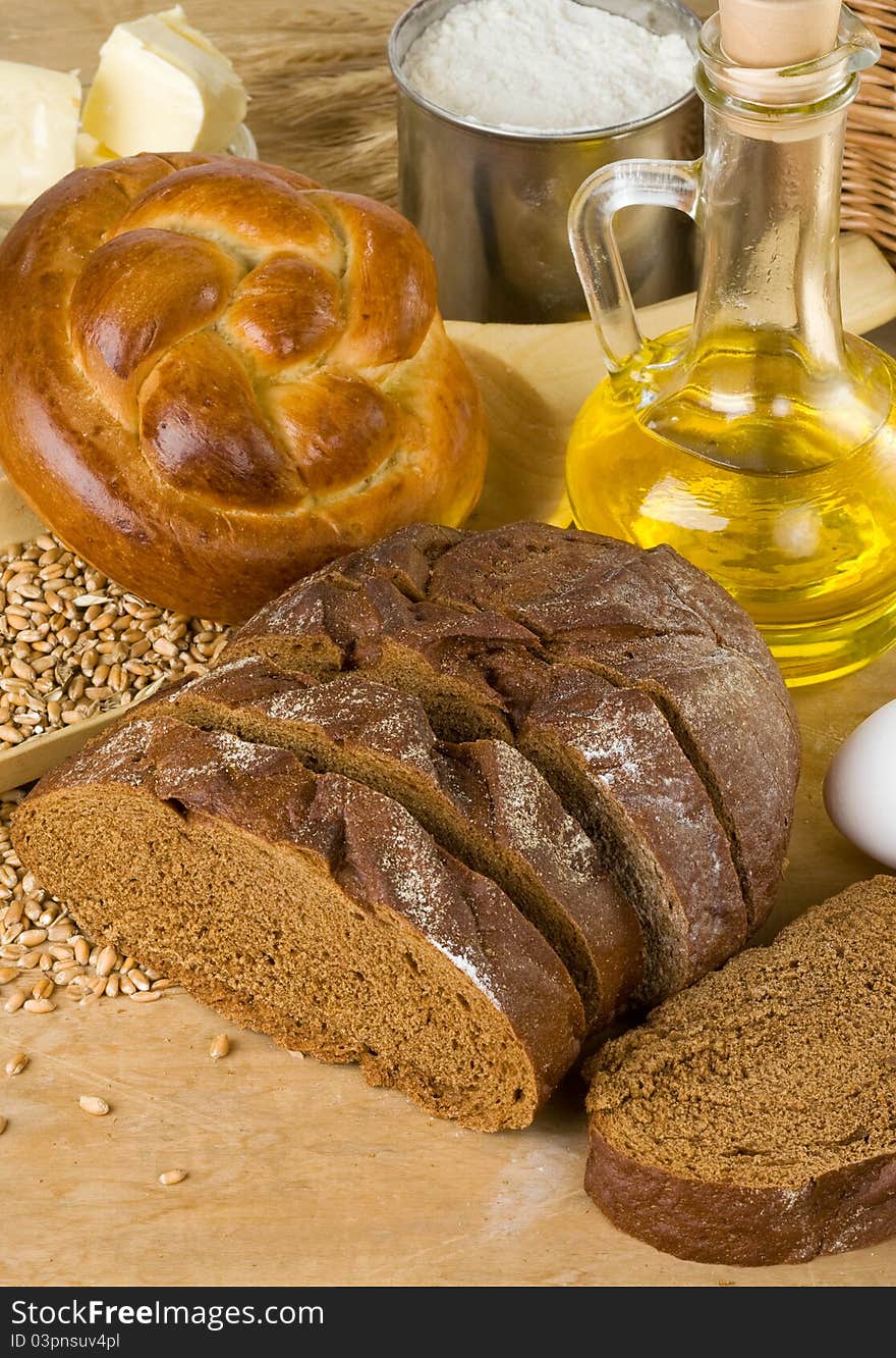 Bakery products and grain on wood background