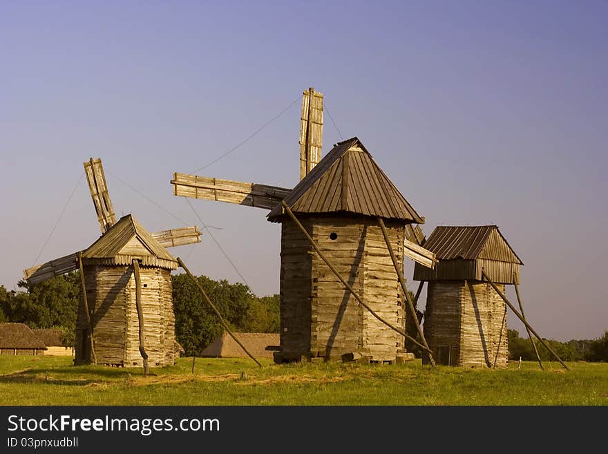 Three old wooden mill on a blue background. Three old wooden mill on a blue background