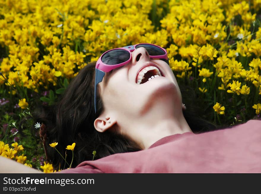 Beautiful young girl with sunglasses laying on yellow flowers