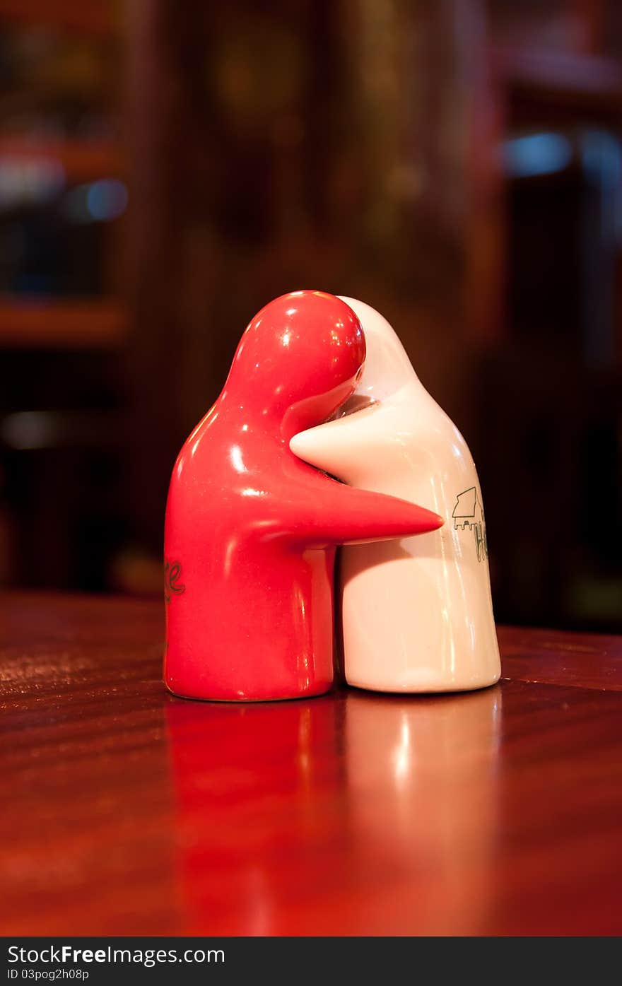 Figures of two saltcellars hugging each other in a candle-light.