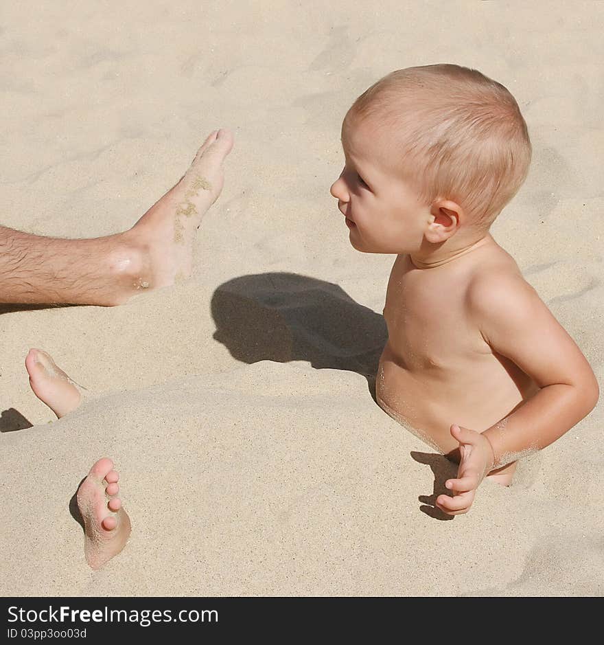 Little boy playing in the sand with his father