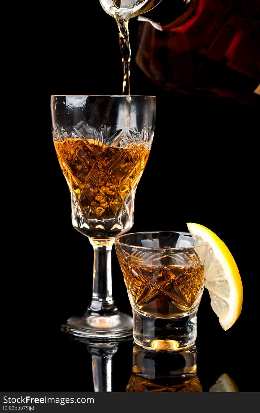 Glass of cognac with lemon isolated on a black background