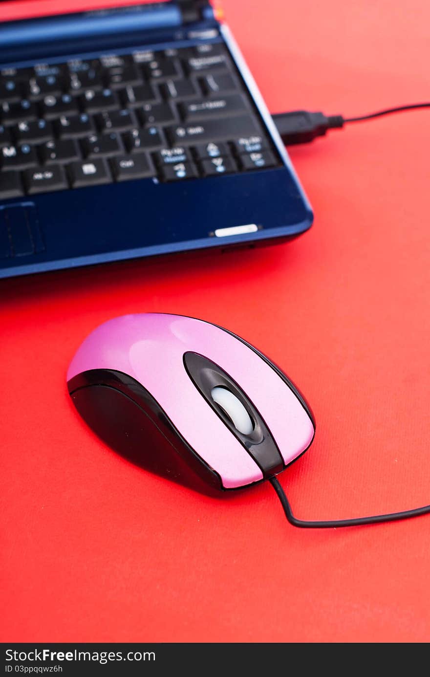 Pink usb mouse and laptop on red background. Pink usb mouse and laptop on red background