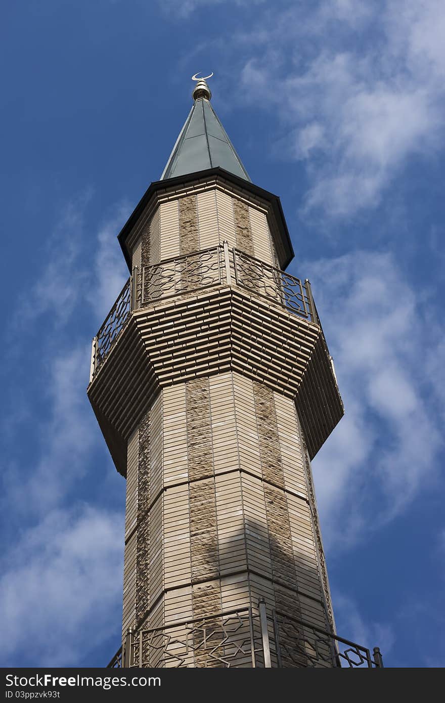 Single minaret against blue sky with clouds