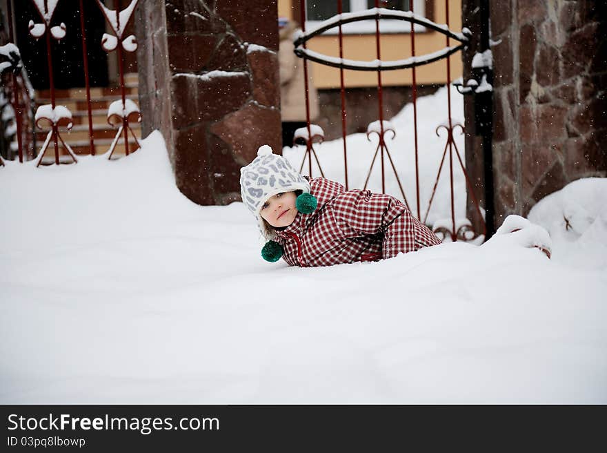 Adorable happy child girl in warm clothes is lying in the snow. Adorable happy child girl in warm clothes is lying in the snow