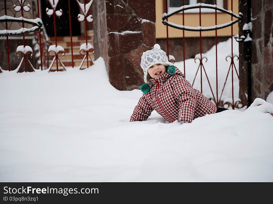 Adorable happy child girl in warm clothes is lying in the snow. Adorable happy child girl in warm clothes is lying in the snow