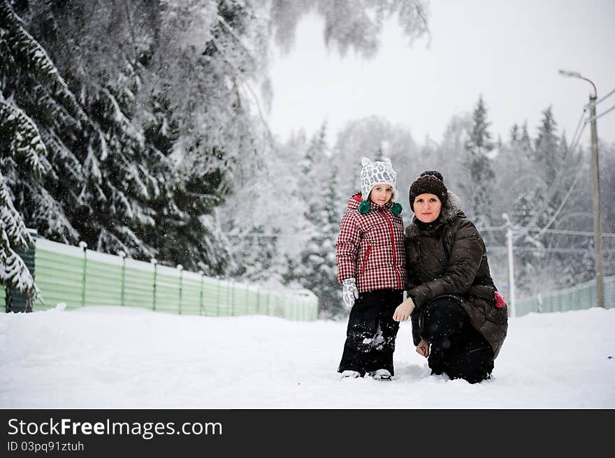 Portrait of young mother and her adorable daughter in the snow on a bright winter day. Portrait of young mother and her adorable daughter in the snow on a bright winter day