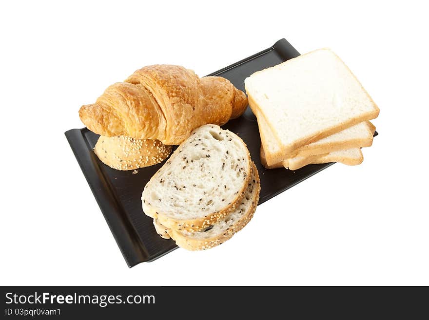 Bread, sesame, white bread and croissant on black tray.