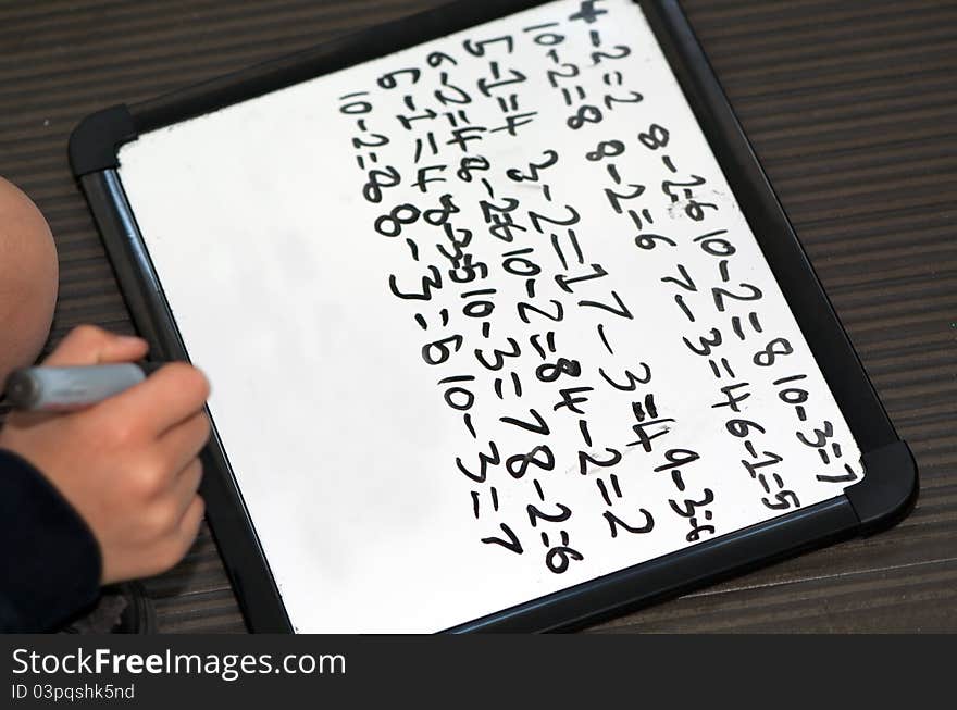 Primary school child doing simple subtractions on white board. Primary school child doing simple subtractions on white board