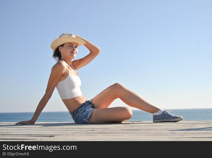 Young woman sitting on the beach in straw hat. Young woman sitting on the beach in straw hat