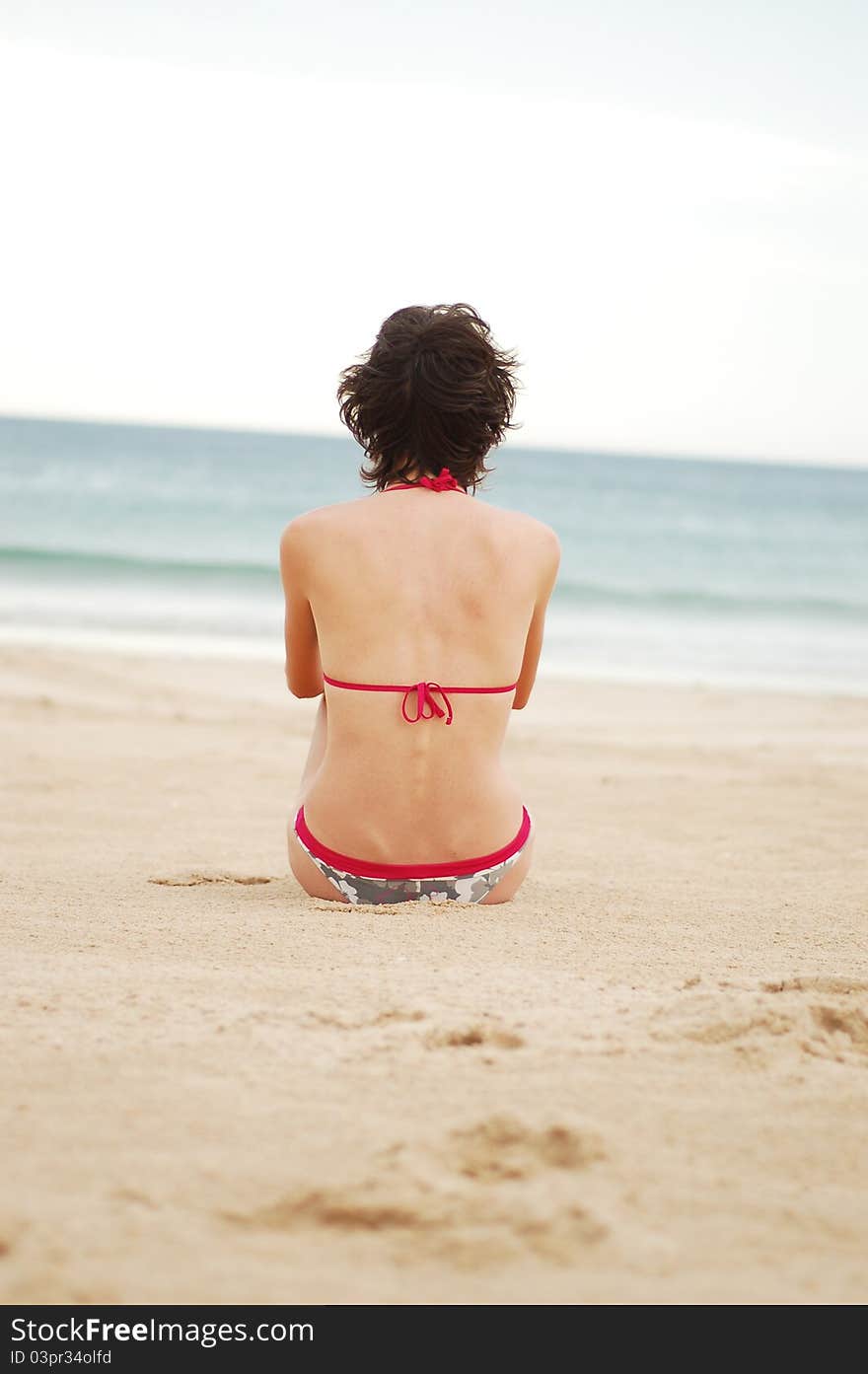 Young woman on the beach near the sea meditating