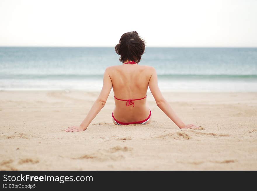 Young woman on the beach near the sea meditating