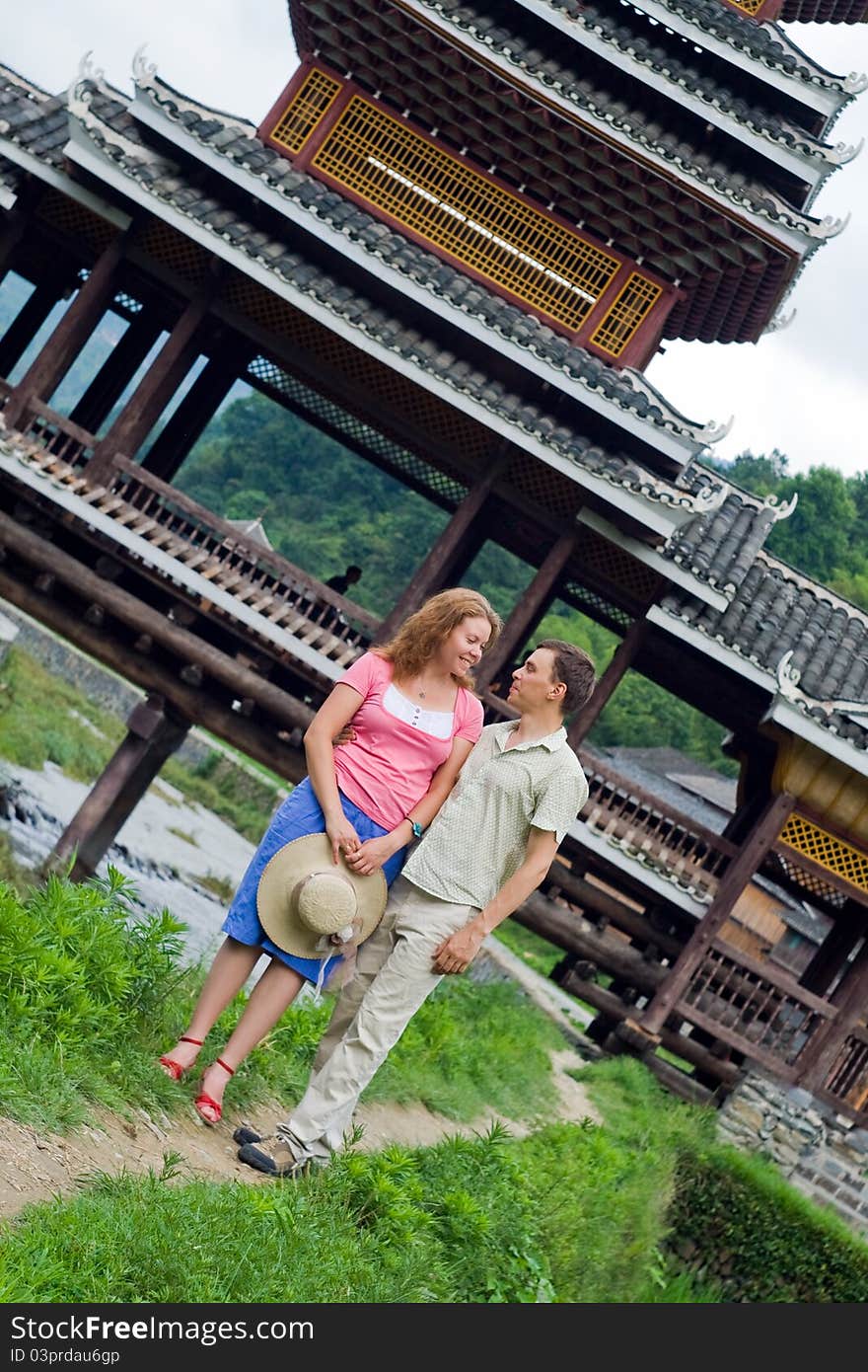 Portrait image of lovely couple. Beauty wearing. Old bridge architecture on the background.