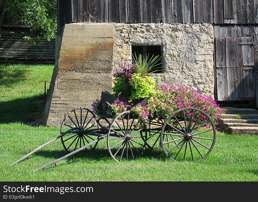 Flowers on horse drawn wagon next to a barn. Flowers on horse drawn wagon next to a barn