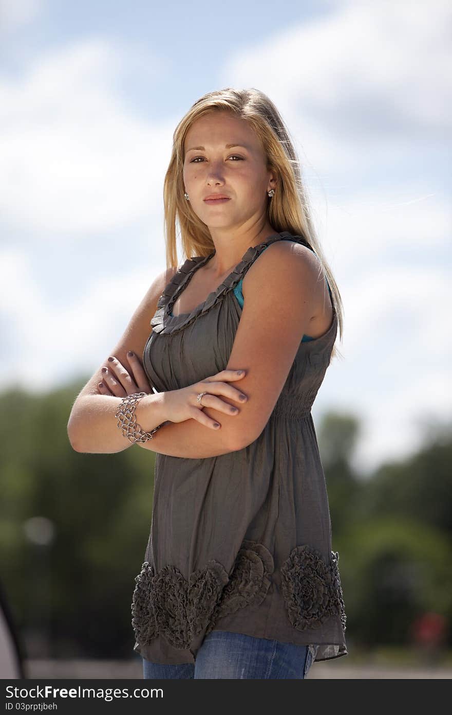 Beautiful young blond model posing outside with arms crossed