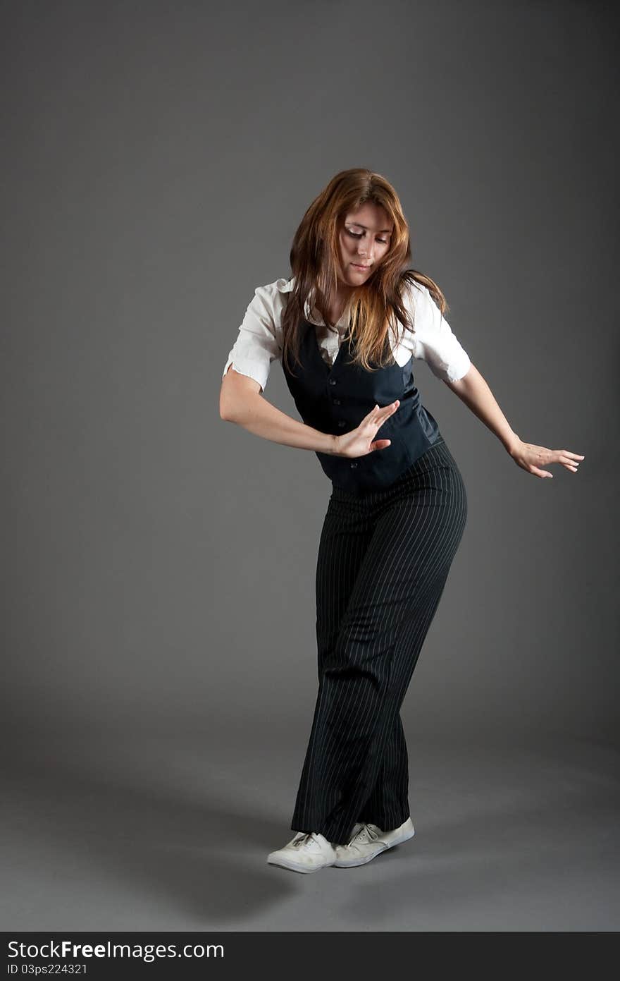 Caucasian female jazz dancer poses in front of a studio gray backdrop.