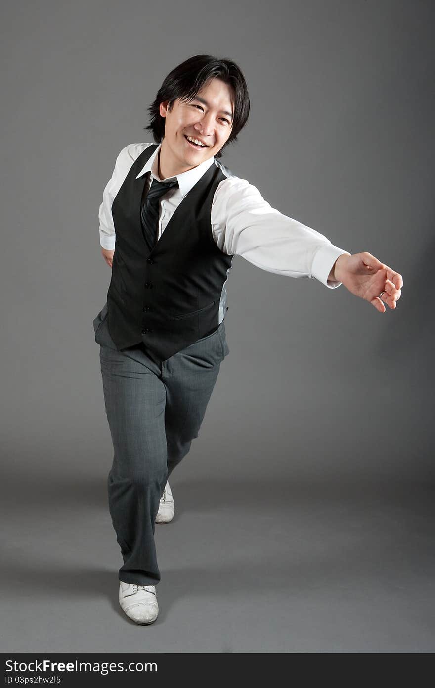 Asian male jazz dancer poses in front of studio gray backdrop.