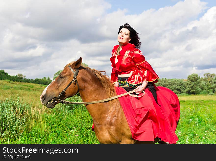 Beautiful gypsy girl riding a horse in the field