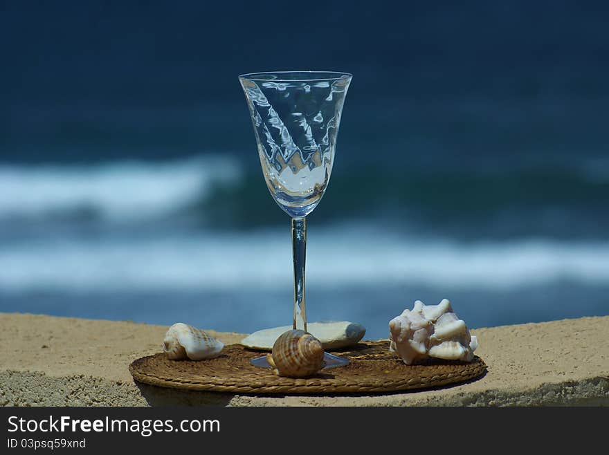 Empty wine glass with sea shells and a reflection of the sky and the sea. Empty wine glass with sea shells and a reflection of the sky and the sea