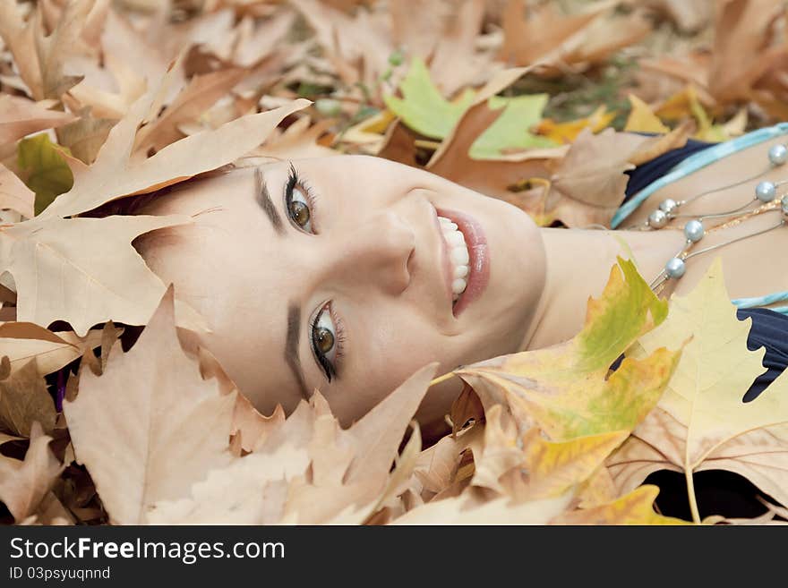 The beautiful woman lies on yellow leaves. The beautiful woman lies on yellow leaves