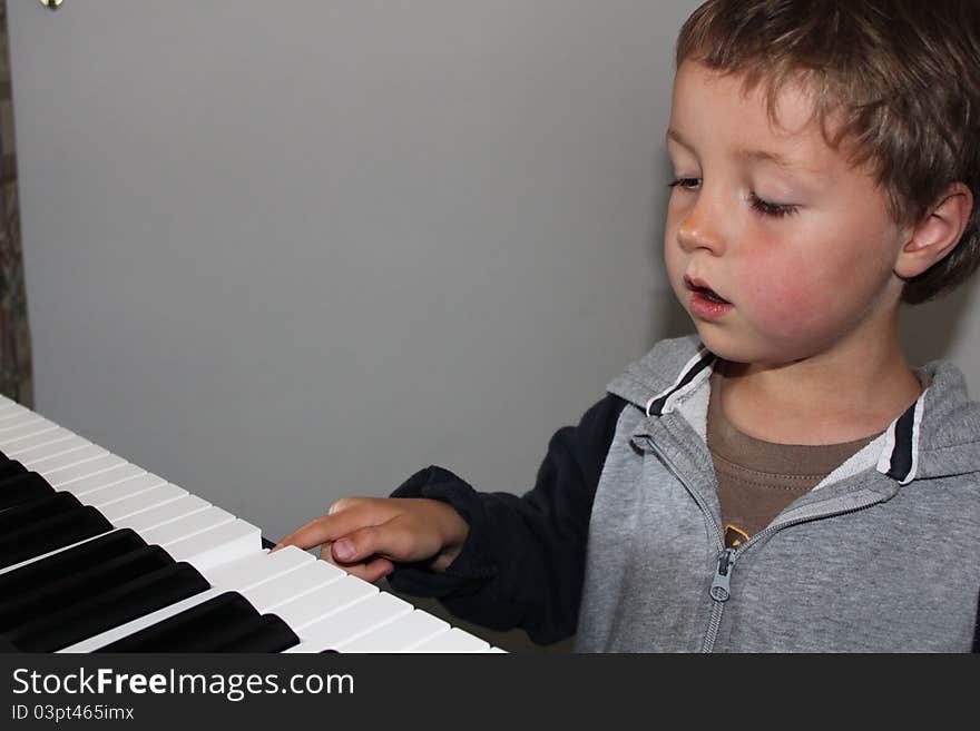 A Young Boy pressing a note on a piano keyboard. A Young Boy pressing a note on a piano keyboard