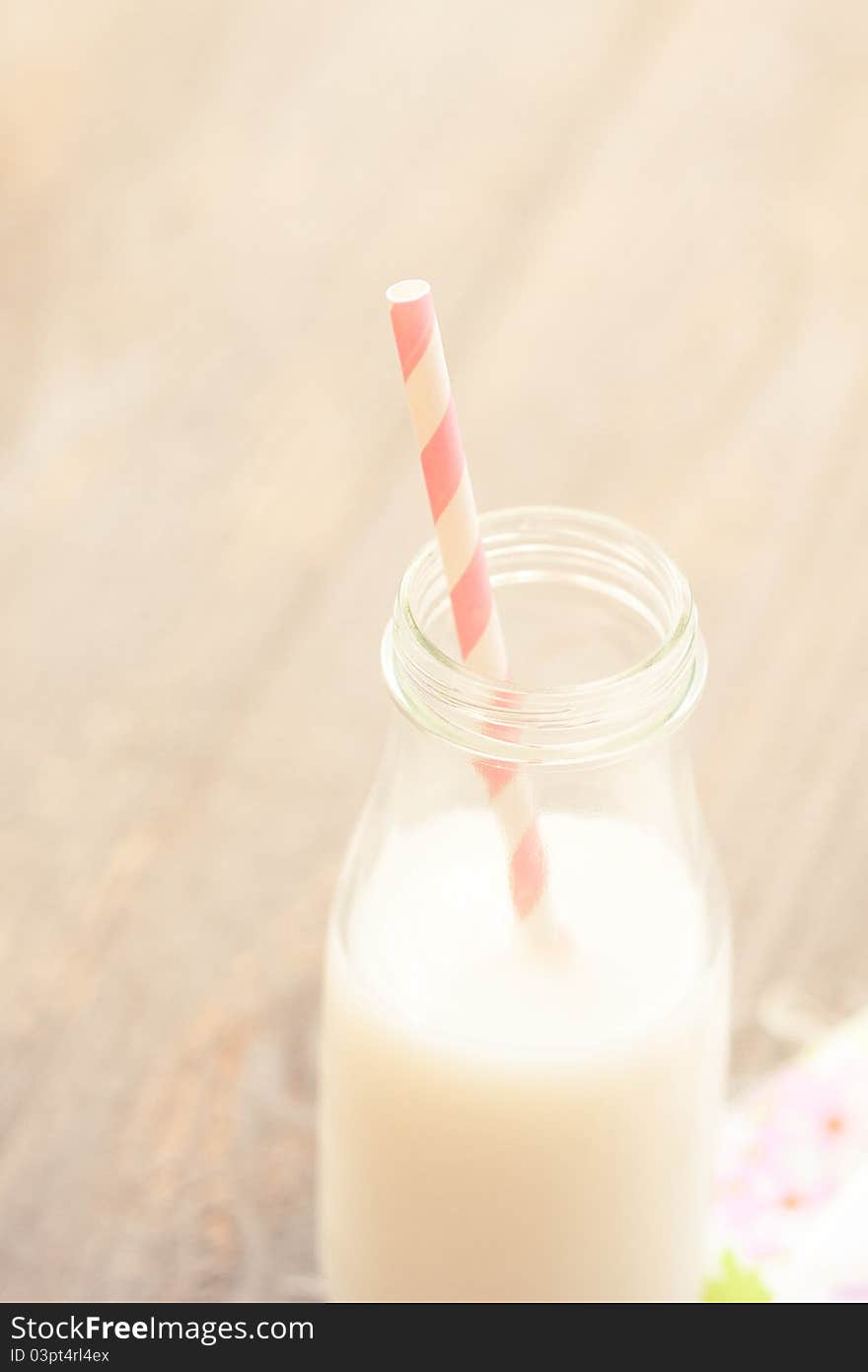 A sweet pink and white striped straw is ready for sipping farm fresh milk out of a glass bottle. A sweet pink and white striped straw is ready for sipping farm fresh milk out of a glass bottle.