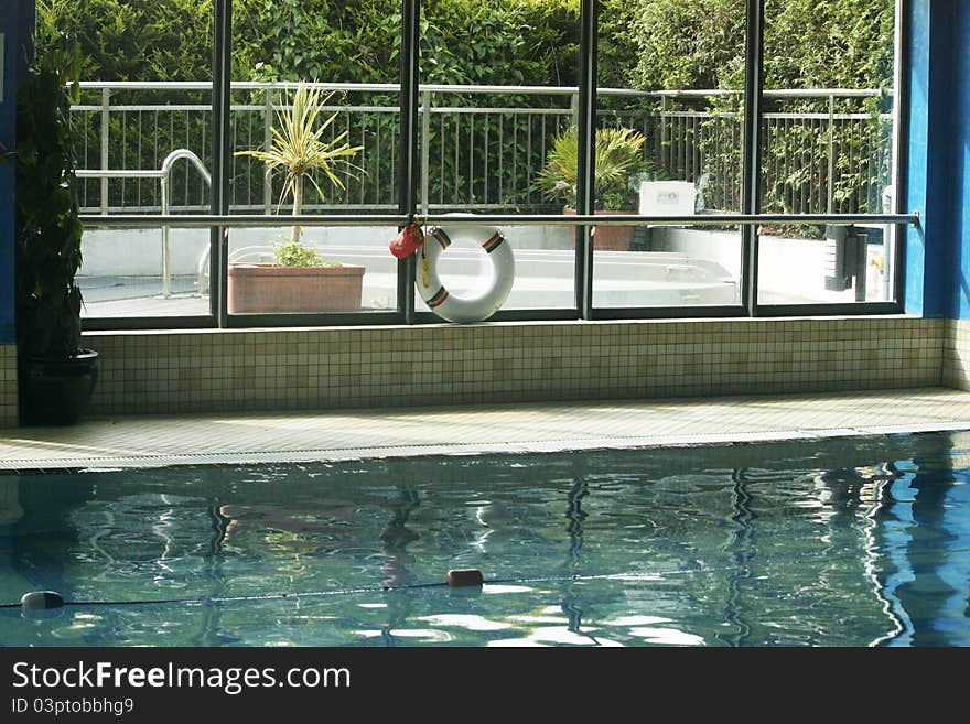 Indoor swimming pool with green plants and spa outside