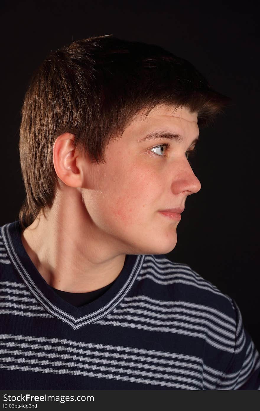 A young boy profile portrait on a black background. A young boy profile portrait on a black background